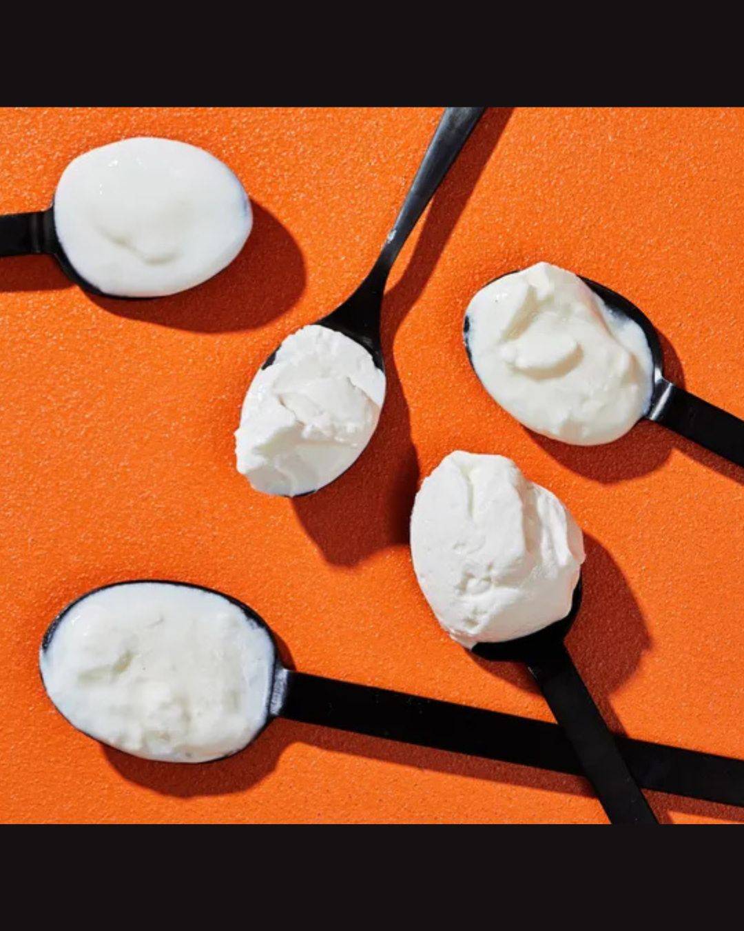 black spoonfuls of white yogurt on orange background