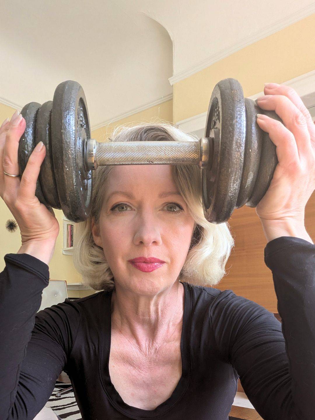 woman holding dumbbell up at forhead