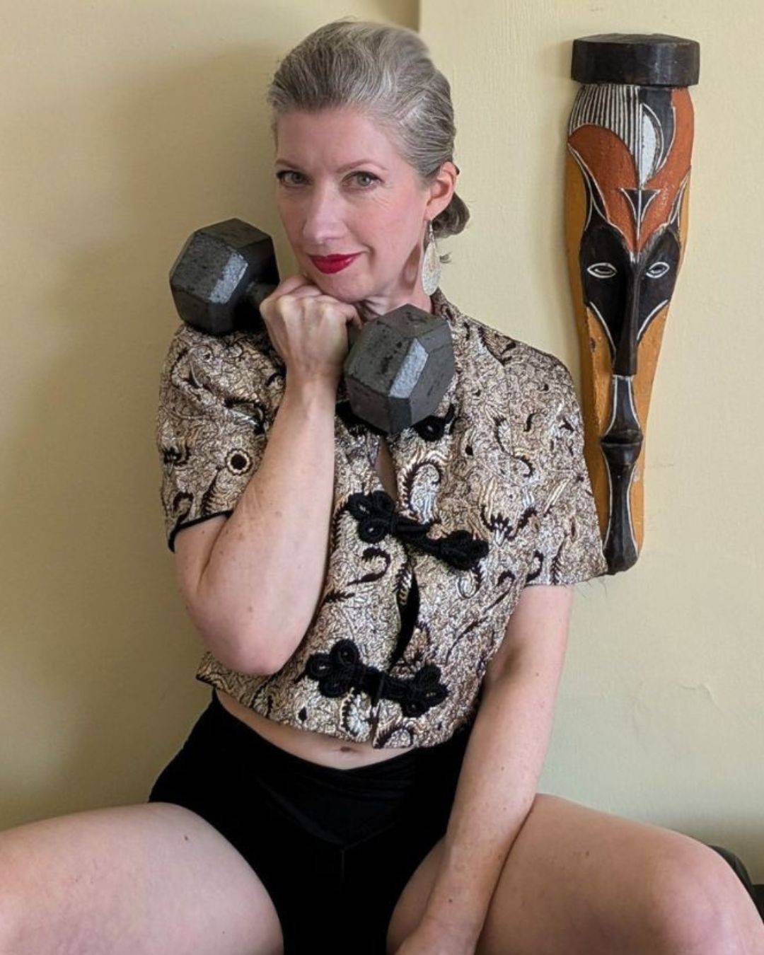 woman in vintage bolero jacket holding weight by chin