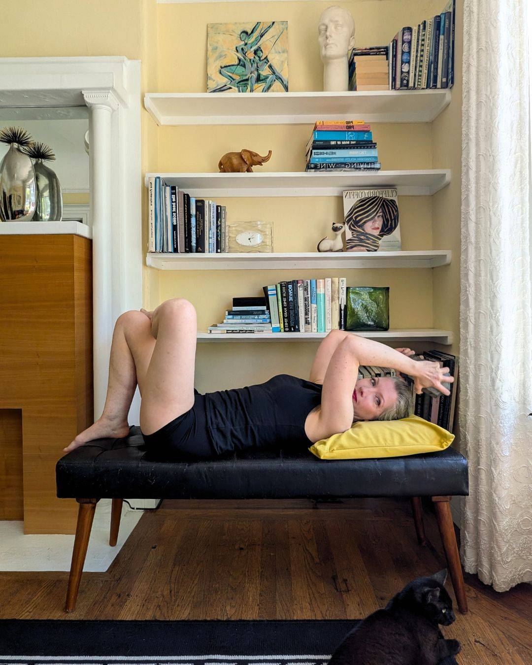 woman lying on black bench doing a triceps press