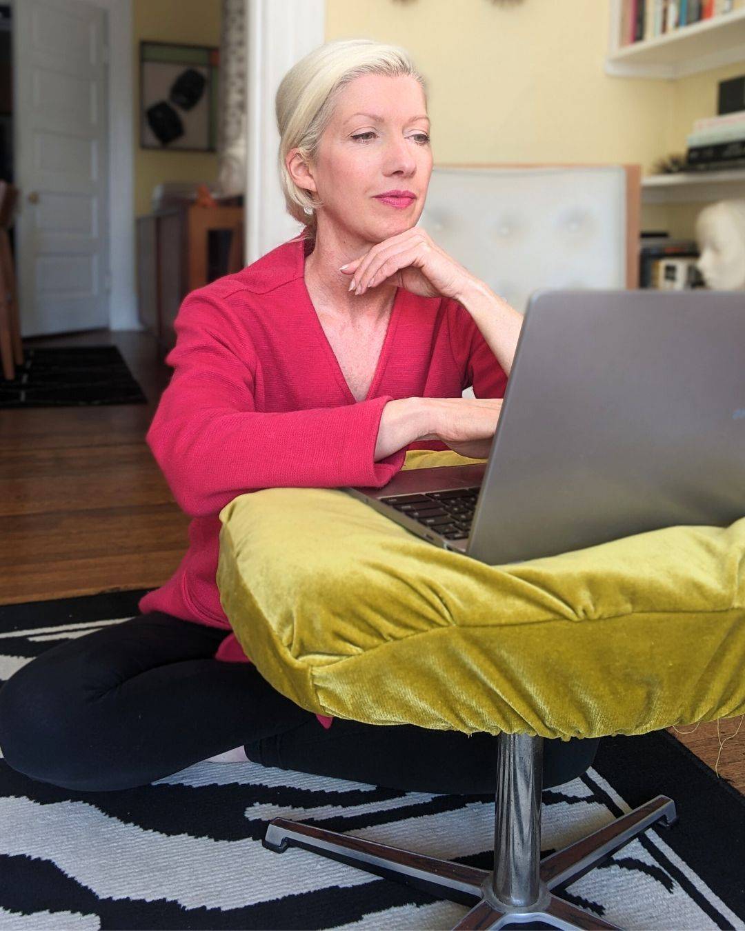 blonde woman in pink top sitting on floor in front of Chromebook