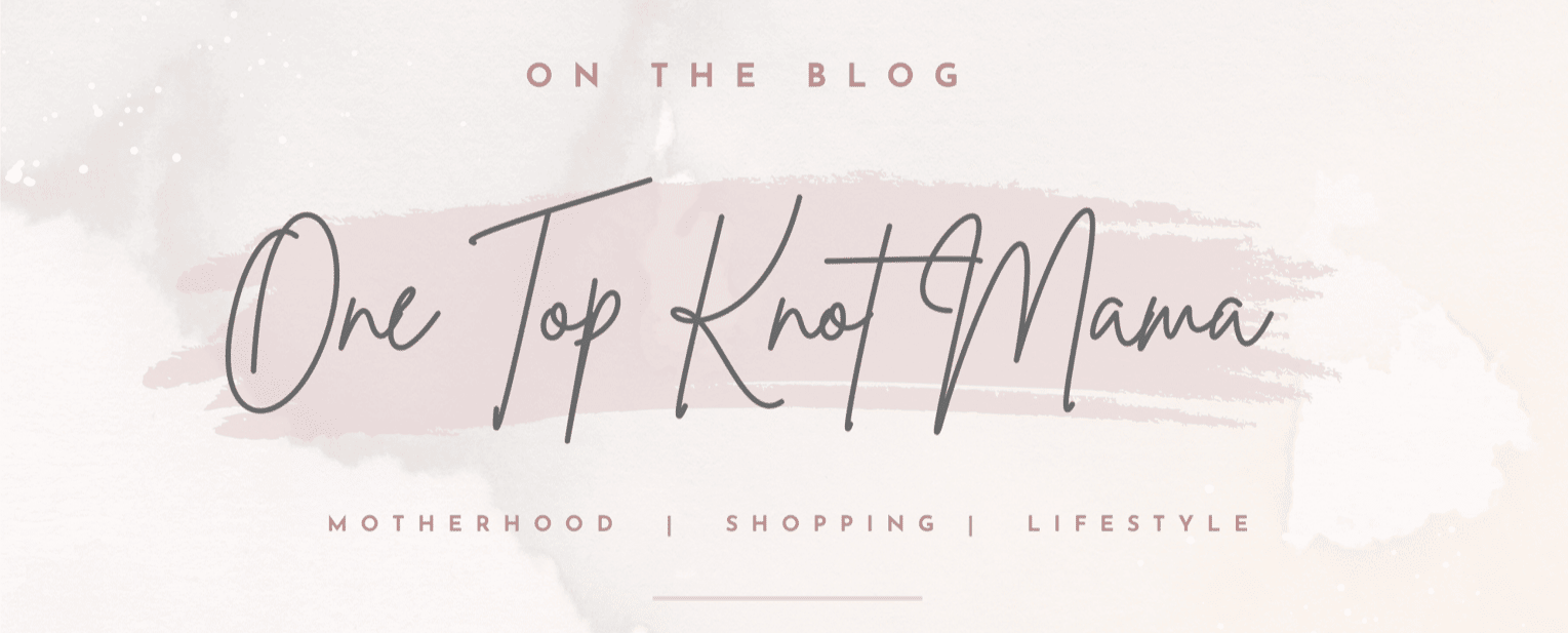 The image features a text with a watercolor background. At the top, it says "On the Blog" in capital letters. Below it, "One Top Knot Mama" is written in a large cursive font. Underneath, there are three categories listed: "Motherhood," "Shopping," and "Lifestyle," separated by vertical lines. The overall color scheme is soft and pastel, predominantly in light pink and gray tones.