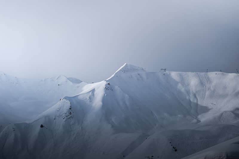 A mountain covered in snow under a cloudy sky