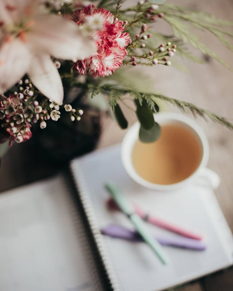 A cup of coffee sitting on top of a table next to a notebook