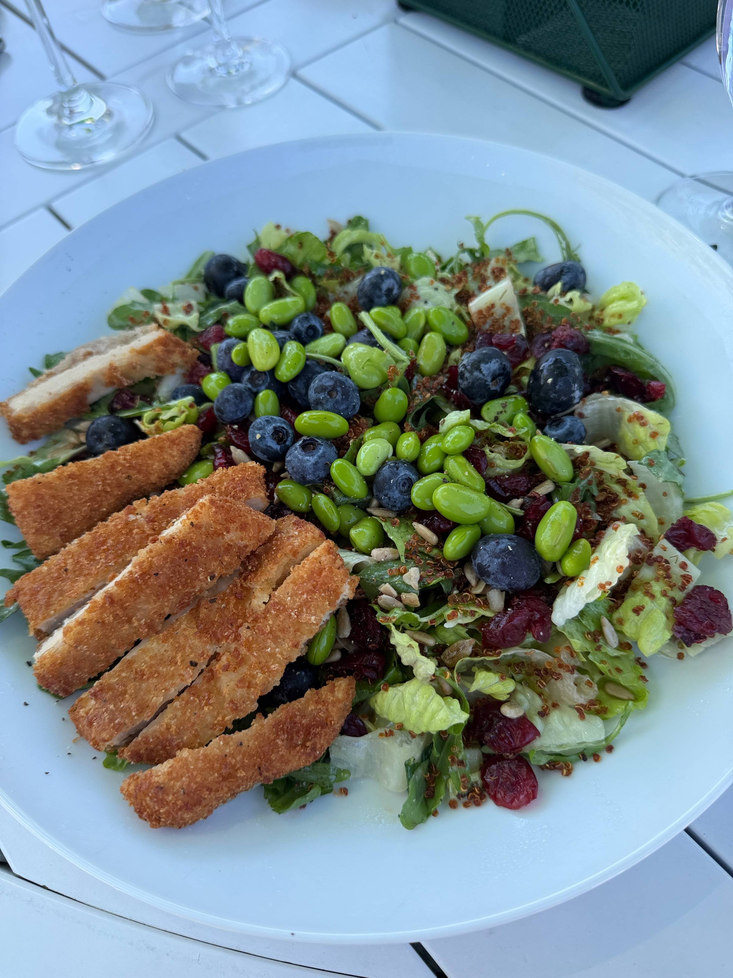 Salad of mixed greens, blueberries, edamame, beets, and red quinoa topped with crispy plant-based cutlet strips.