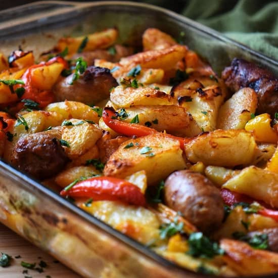 Sausage, potatoes, peppers and onions in a casserole dish.