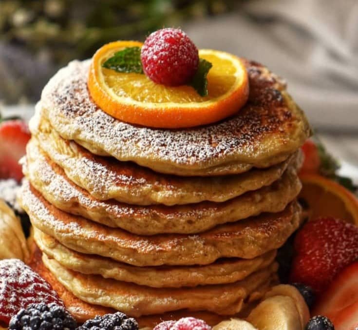 A stack of oatmeal pancakes garnished with fresh fruit.