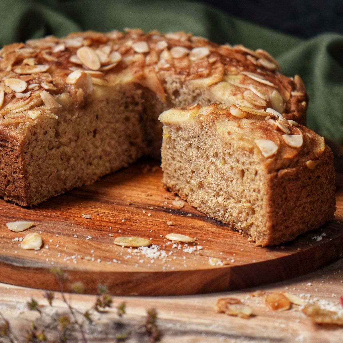 A slice of pear cake on a wooden cutting board.