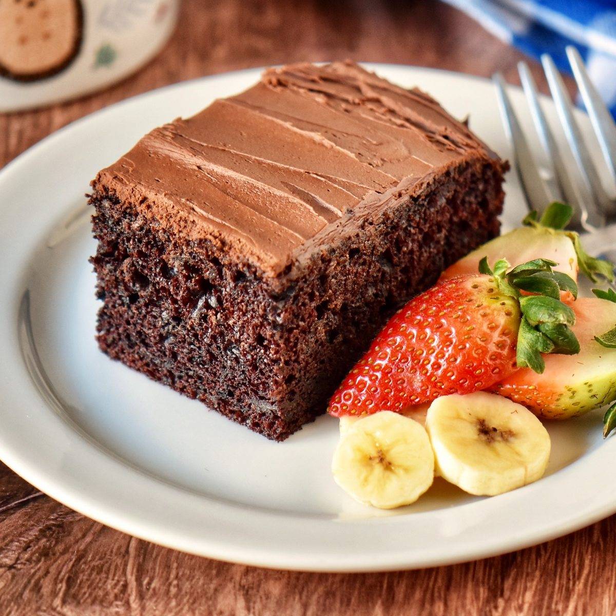 Chocolate Banana Cake on a white plate garnished with sliced bananas and strawberries.
