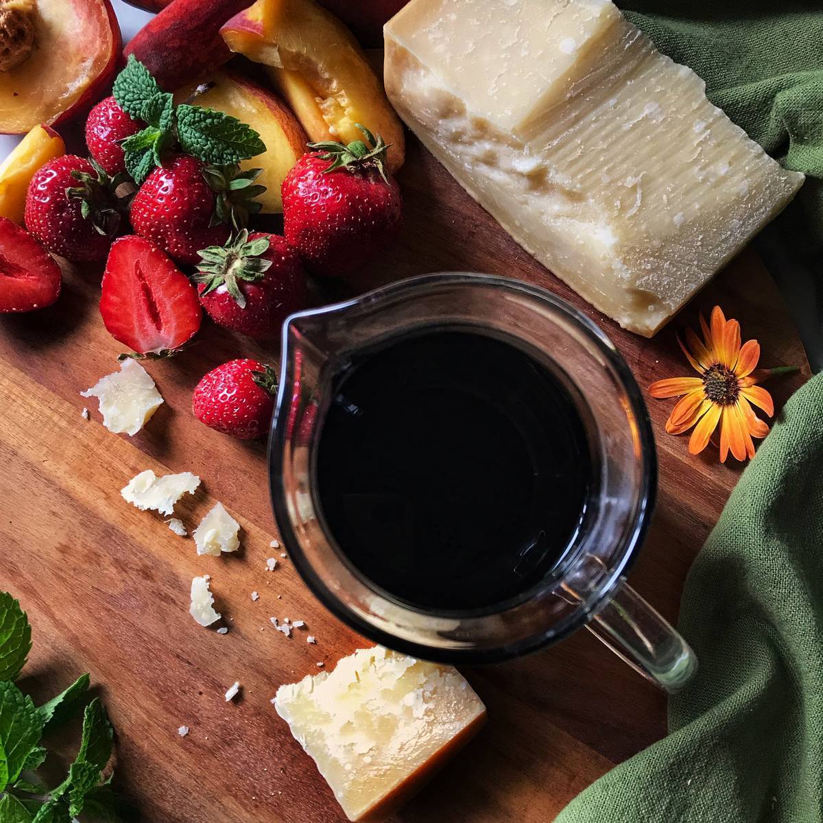 Balsamic glaze in a jar, next to fresh strawberries.