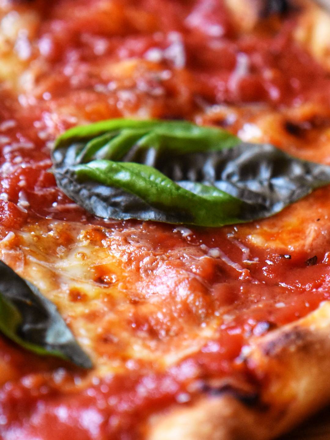 Margherita pizza with a basil leaf.