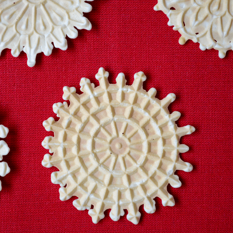 Pizzelle della nonna are shown on a red tablecloth.