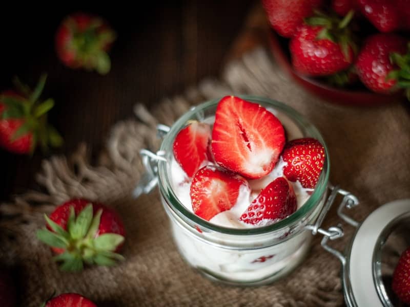 Fresh strawberries with cream in a glass jar