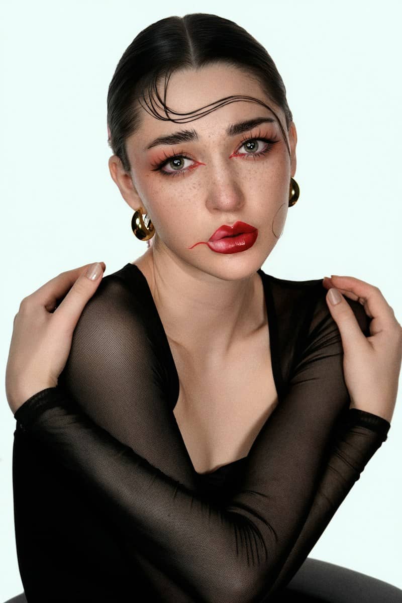 Woman with dramatic makeup and slicked hair poses.
