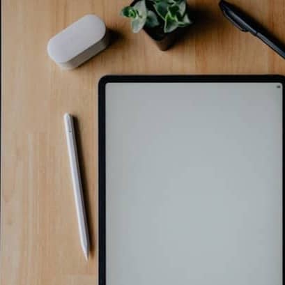 Tablet, accessories, and coffee on a wooden desk.
