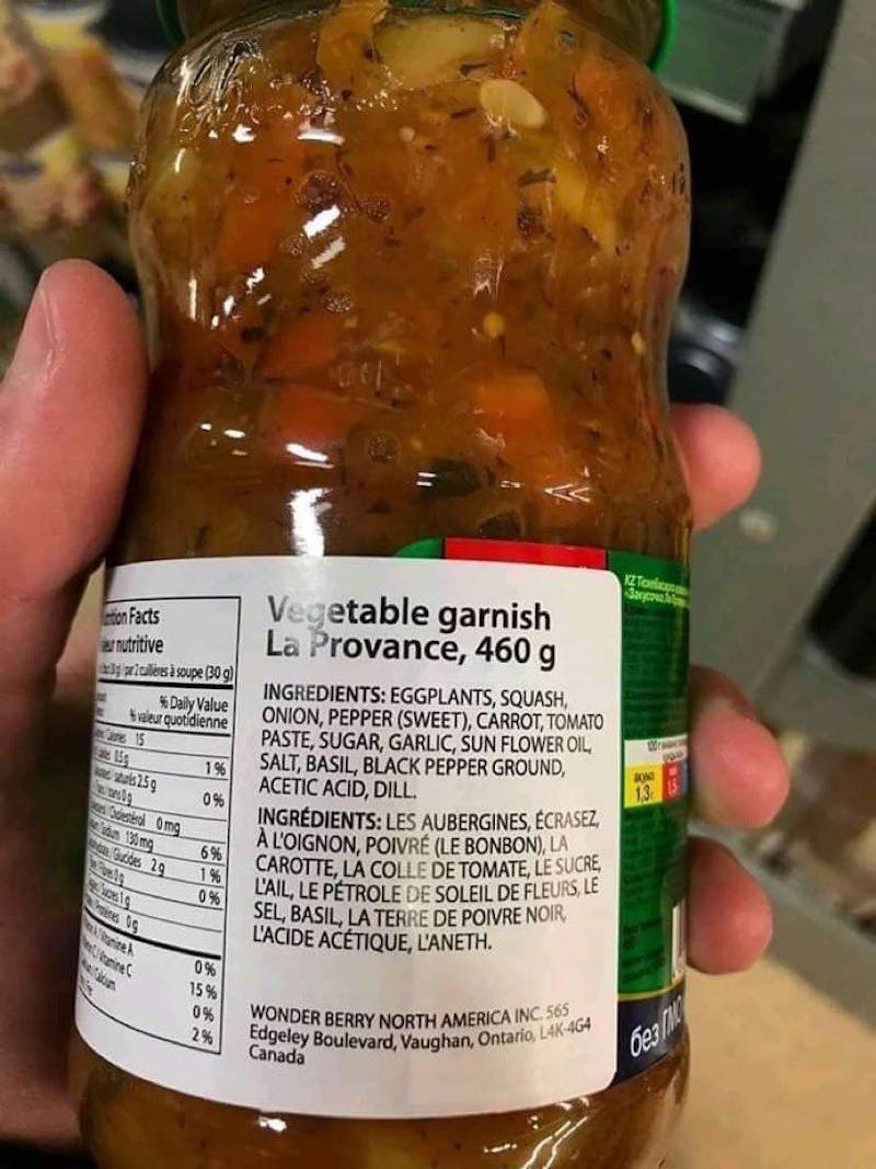 Une photo montrant de près une étiquette d'une bouteille de sauce: les noms des ingrédients traduits à la machine incluent « écrasez à l'oignon » pour « crushed onion » ou « pétrole de soleil de fleurs » pour « sunflower oil». Incompréhensible!