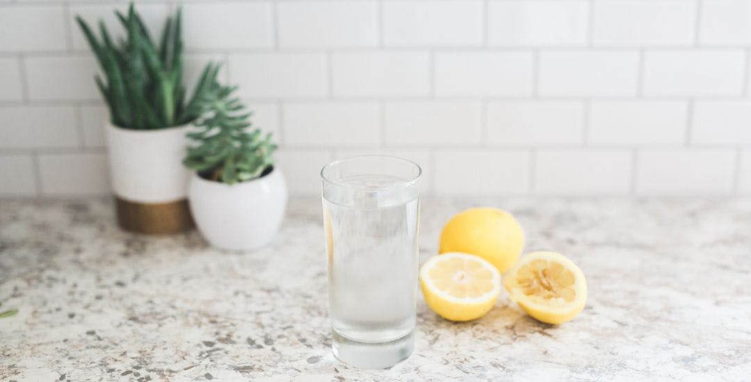 Glass of water with lemons next to it