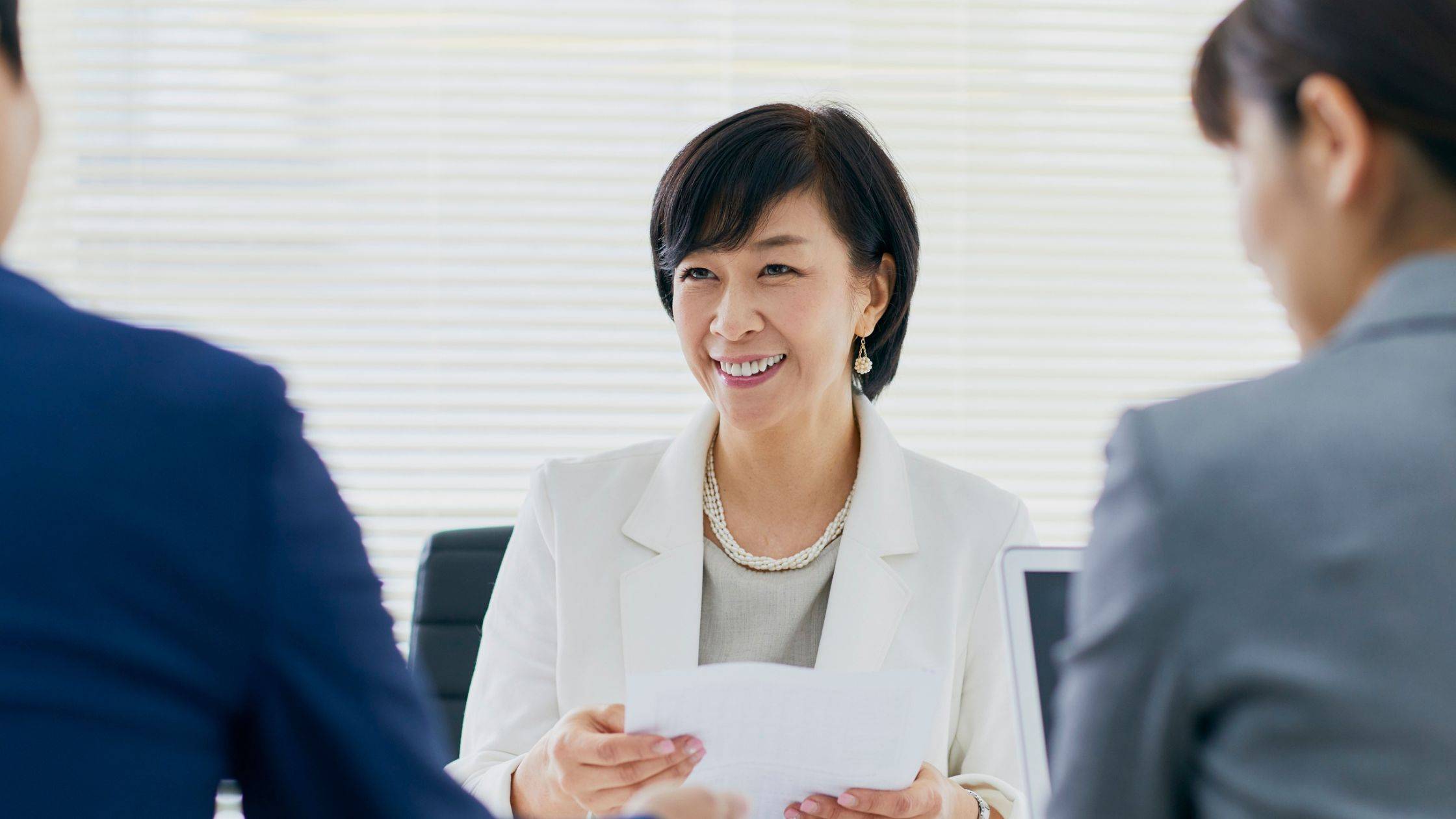 Smiling Asian woman sitting across from two people
