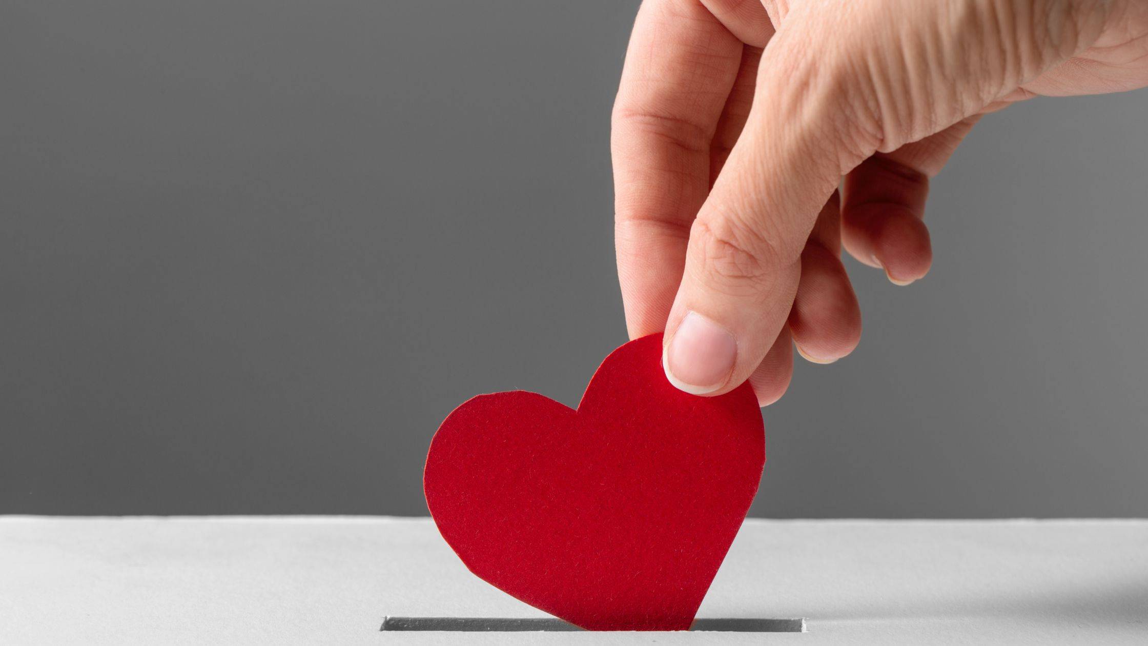 Hand placing a red heart in a box