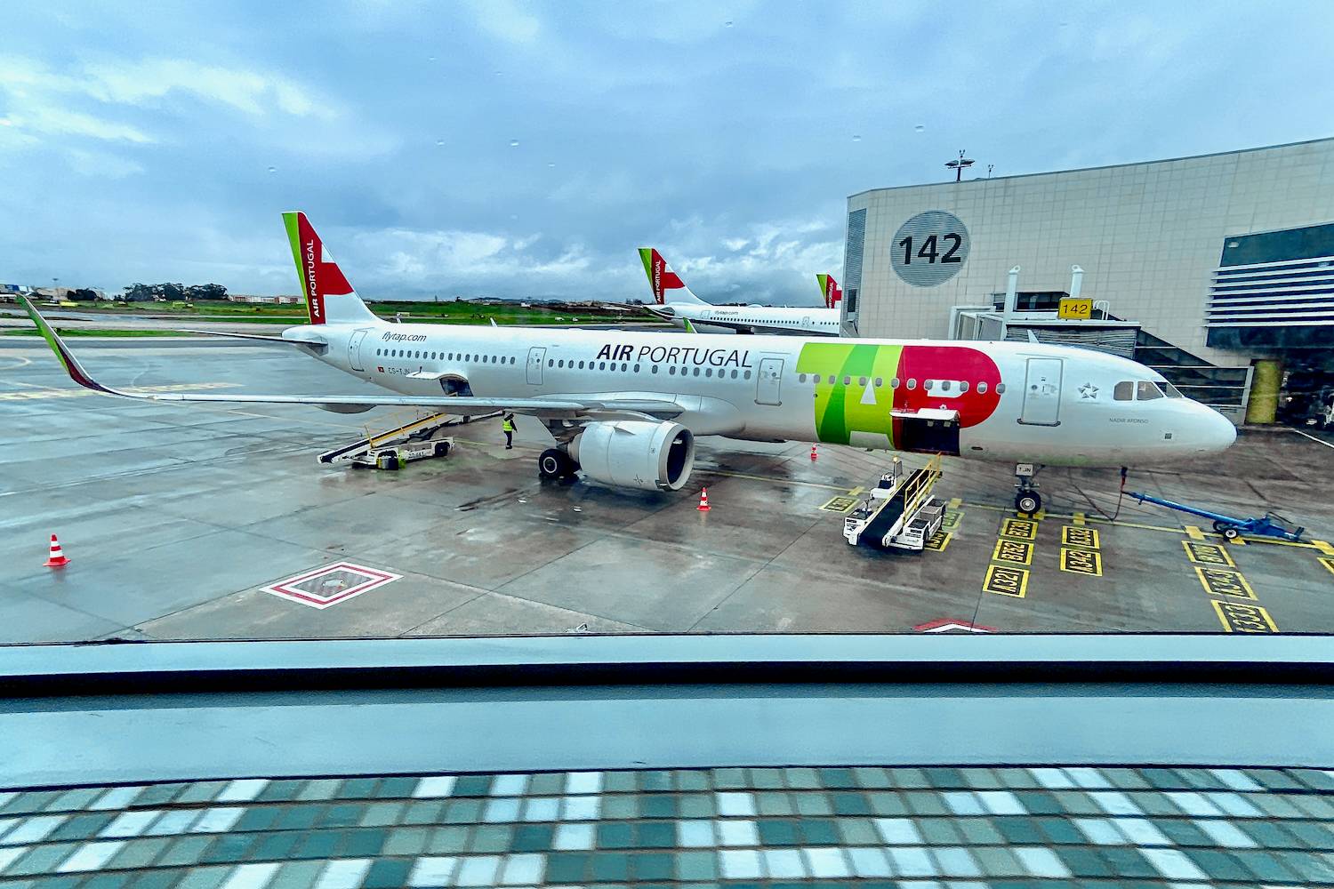 TAP - Air Portugal plane waiting in gate for boarding on an cloudy and rainy day