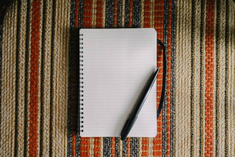 A blank notebook with a pen on striped fabric.