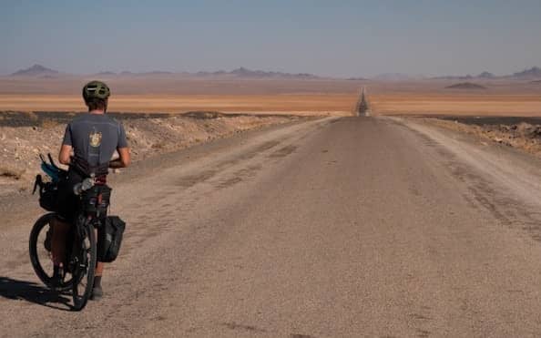 a man riding a bike down a dirt road