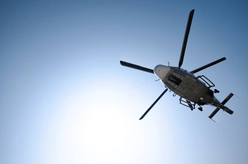A helicopter flying in a clear blue sky.
