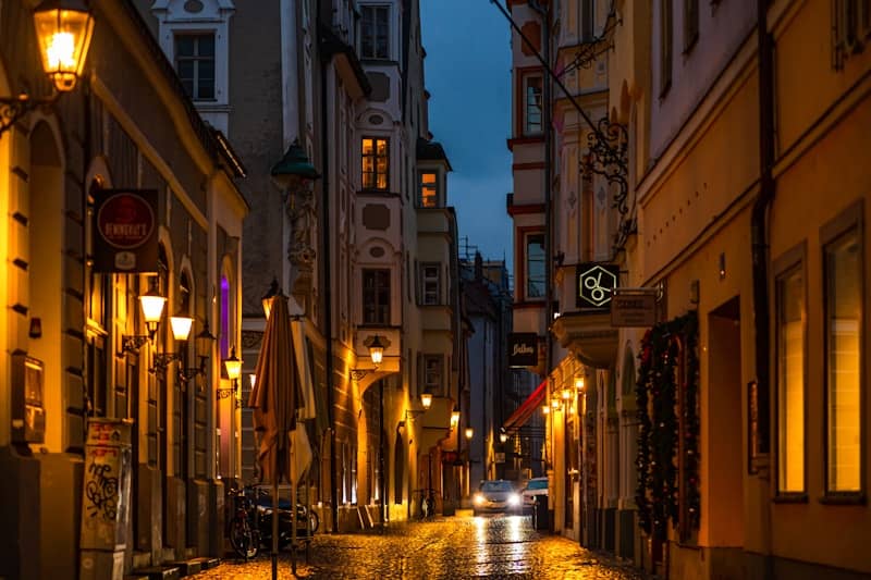 A city street at night with a car driving down it