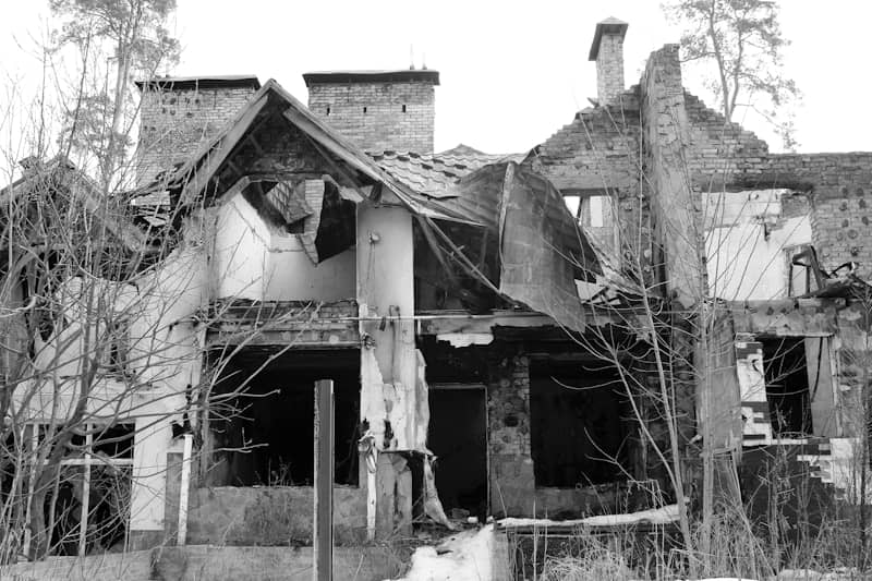 Ruined house with broken roof and windows overgrown trees