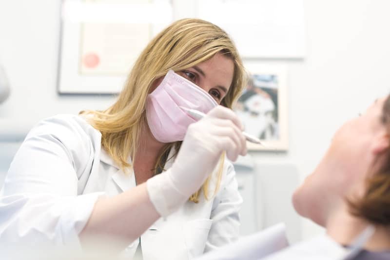 A dentist is examining a patient's mouth.