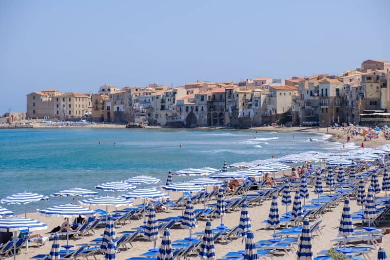 Beach with umbrellas and buildings along the coast.