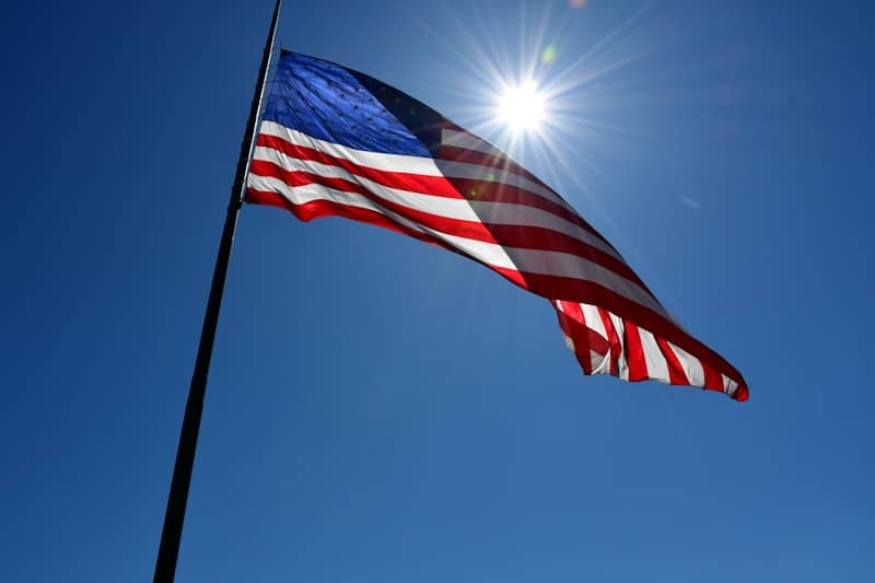 An american flag waves in the sunny sky.