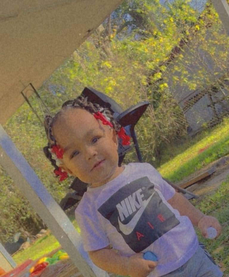 Photo of a young child with braids and red clips in her hair.