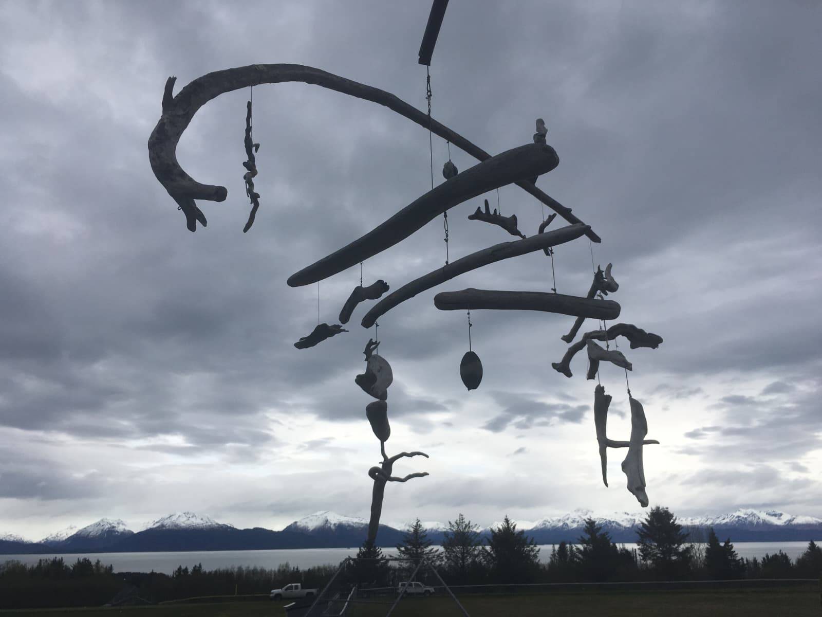 Photo of Michael McBride's driftwood mobile silhouetted against a cloudy sky.