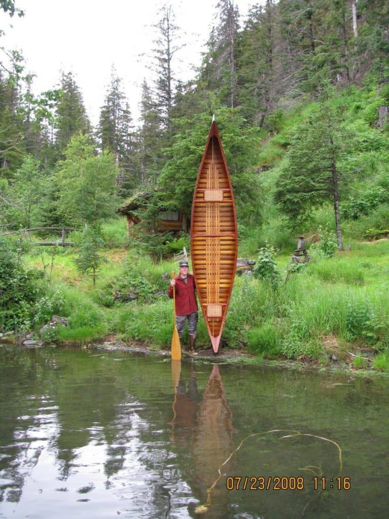 Michael McBride stands near the water with his prized  1929 museum restoration Old Town Canoe.