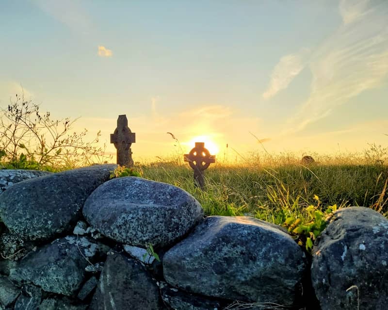 A stone wall with a cross in the background