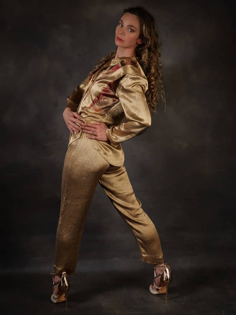 A woman poses in a shiny golden outfit.