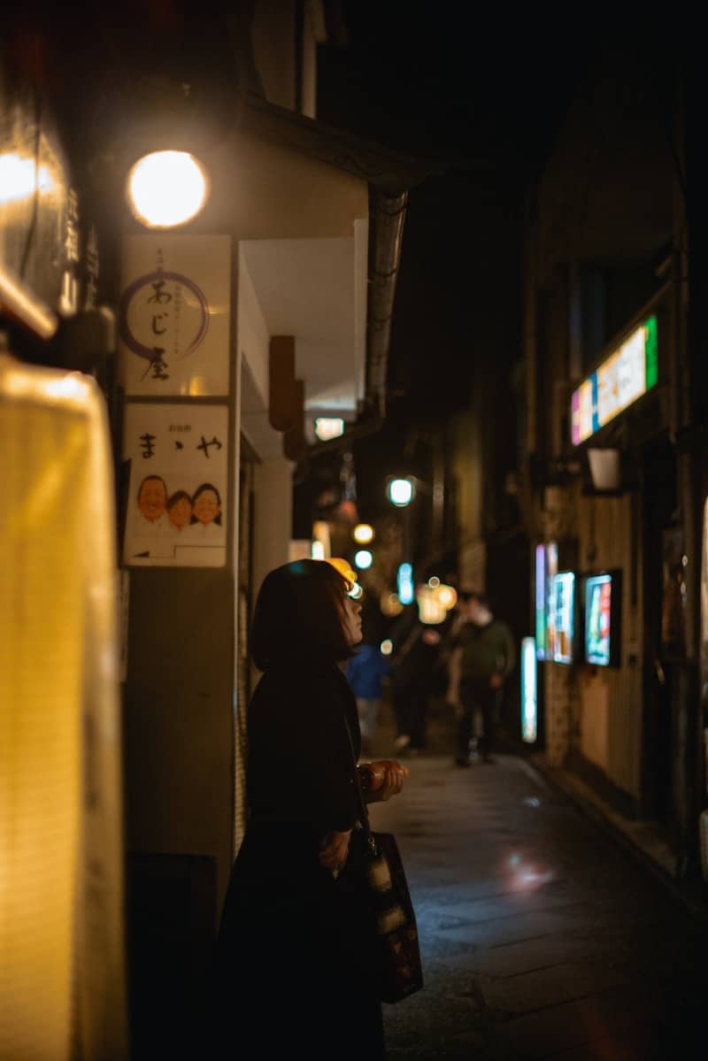 Woman standing on a dimly lit city street at night