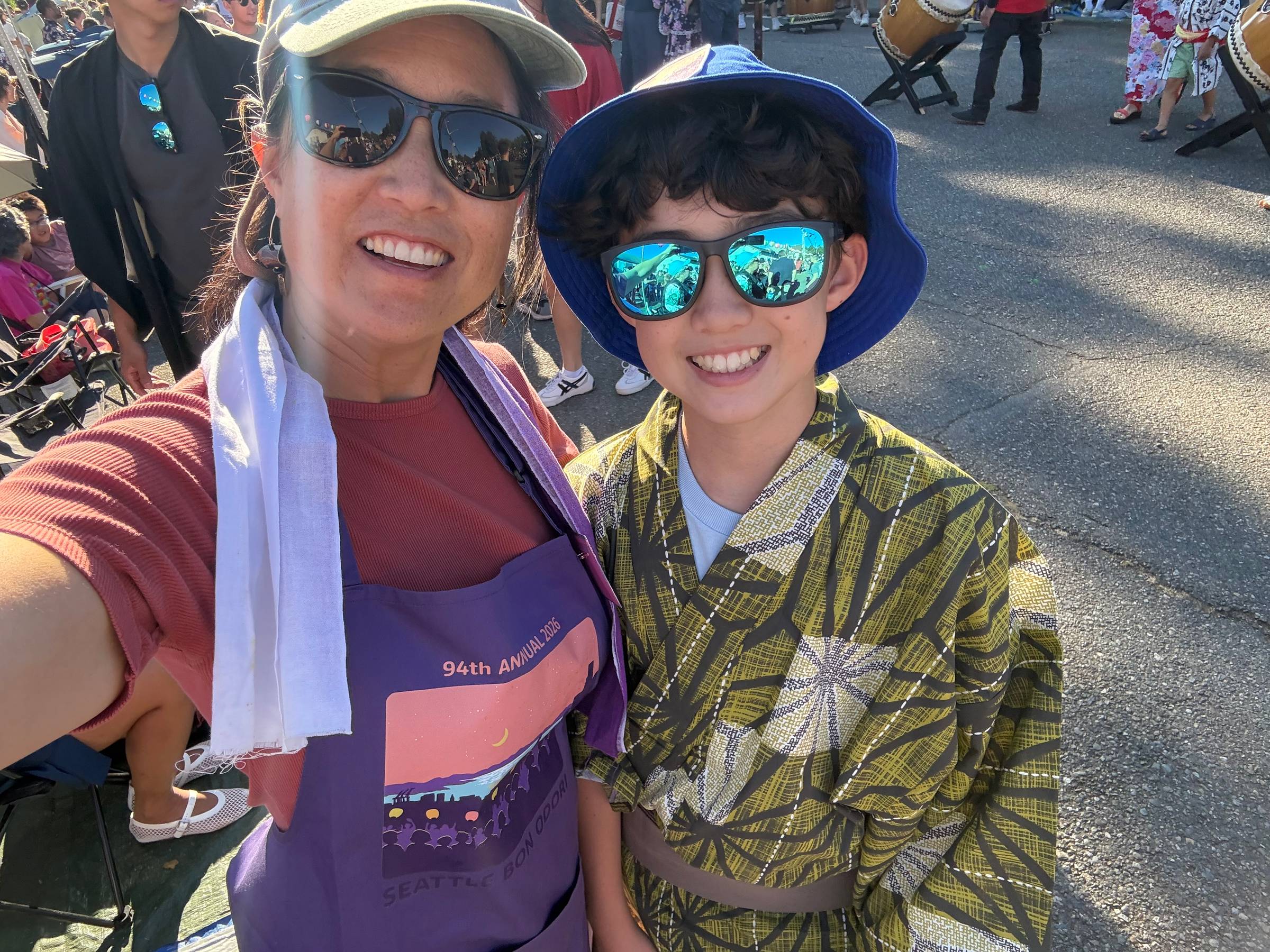 Smiling woman with sunglasses and white cap in an apron with a teen boy in sunglasses and a yukata (Japanese summer wear)