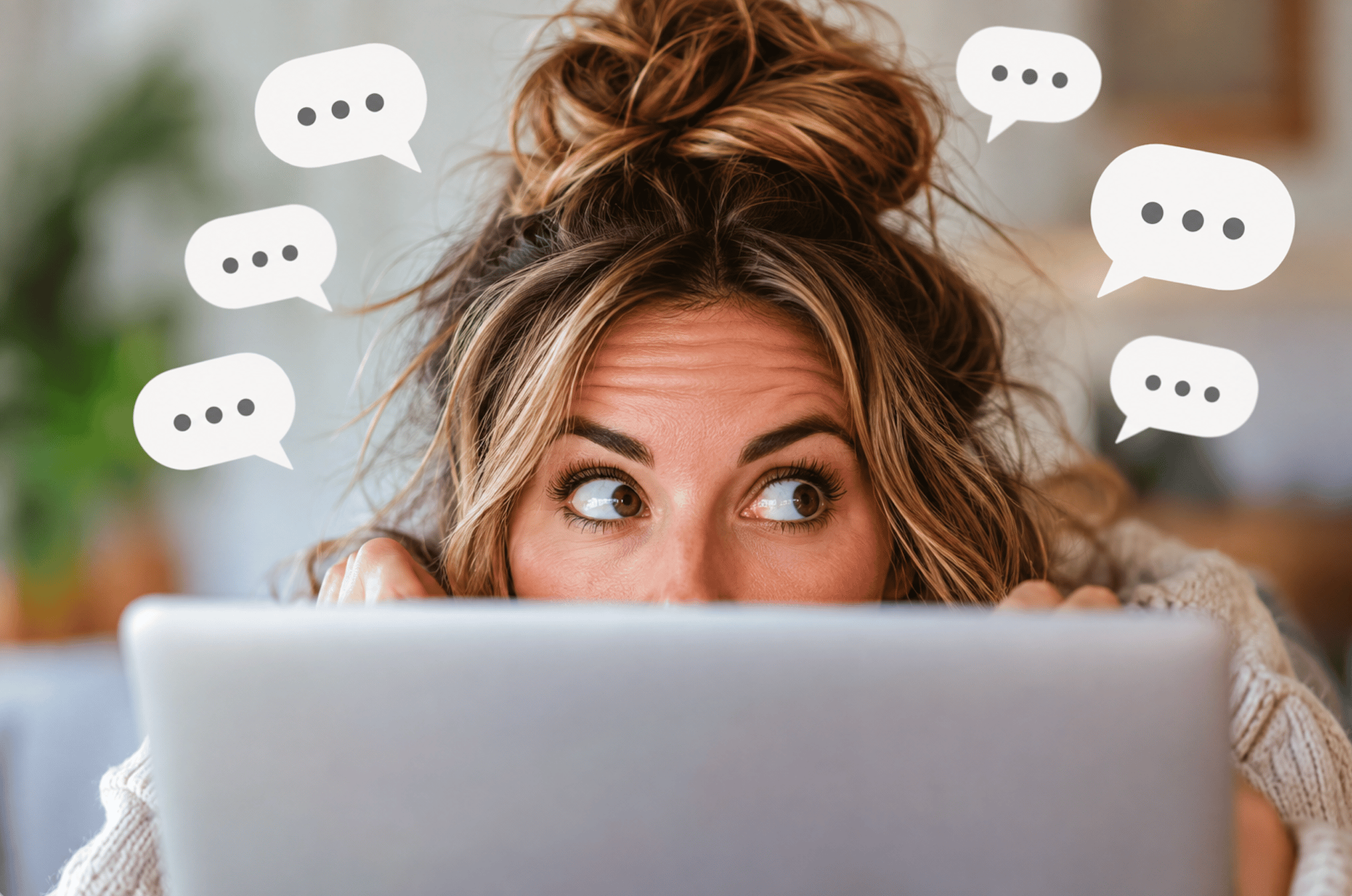 Woman peeking over laptop with chat bubbles