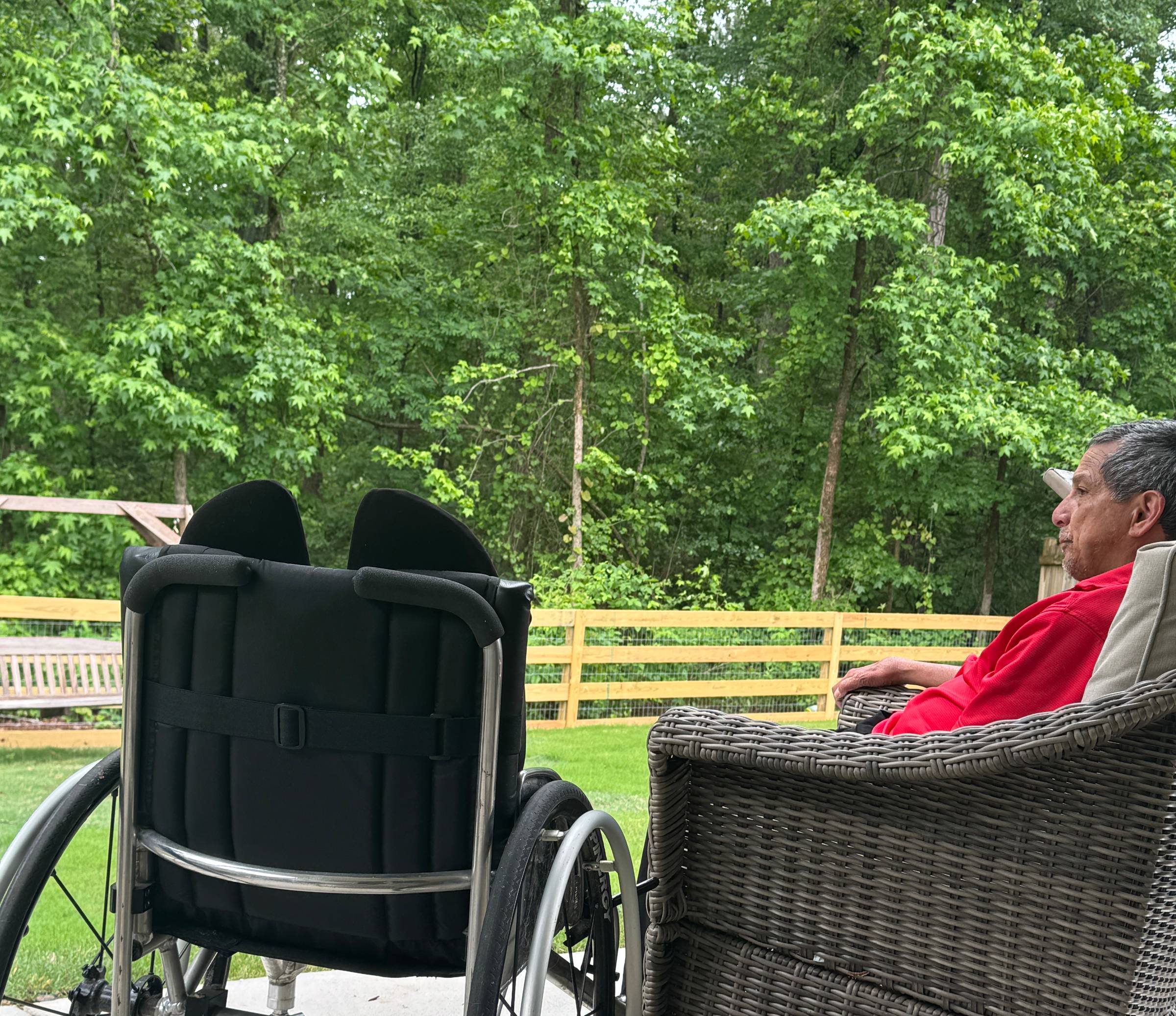 Man sitting on patio with wheelchair beside him.