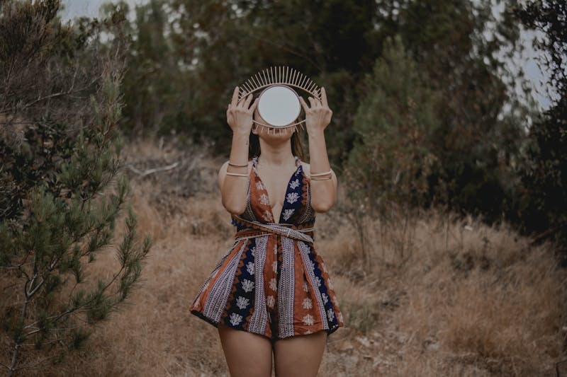 woman in black and red floral dress holding white hat