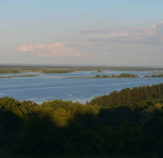 A wide river with forests under a partly cloudy sky.