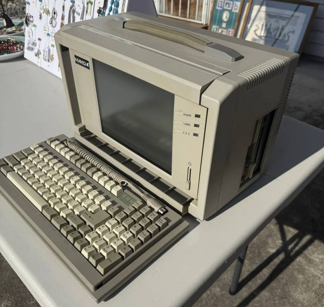 Computer that weighed ~15 lbs, with a black and white screen and a keyboard that attached to the lunchbox-shaped device with a coiled cord