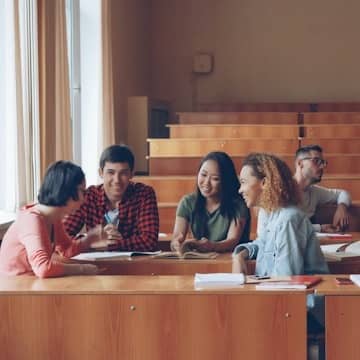 group of college students in a lecture hall talking in a small group