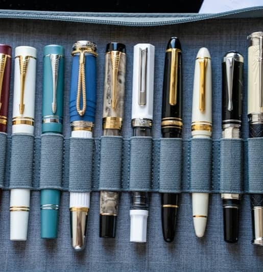 A collection of fountain pens arranged in a grey case.