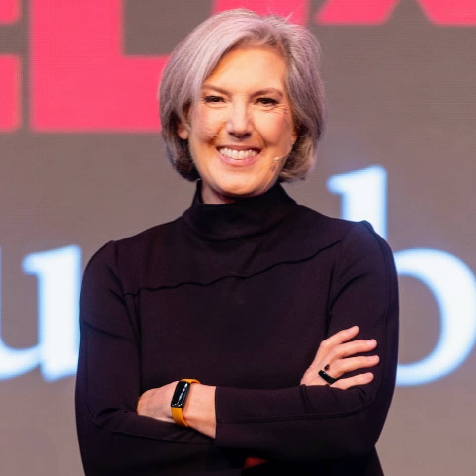 Headshot - Susan Hrach - stands with folded arms and a confident smile