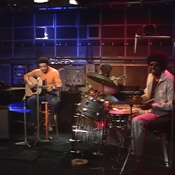 Bill Withers plays the guitar and it accompanied by a drummer
