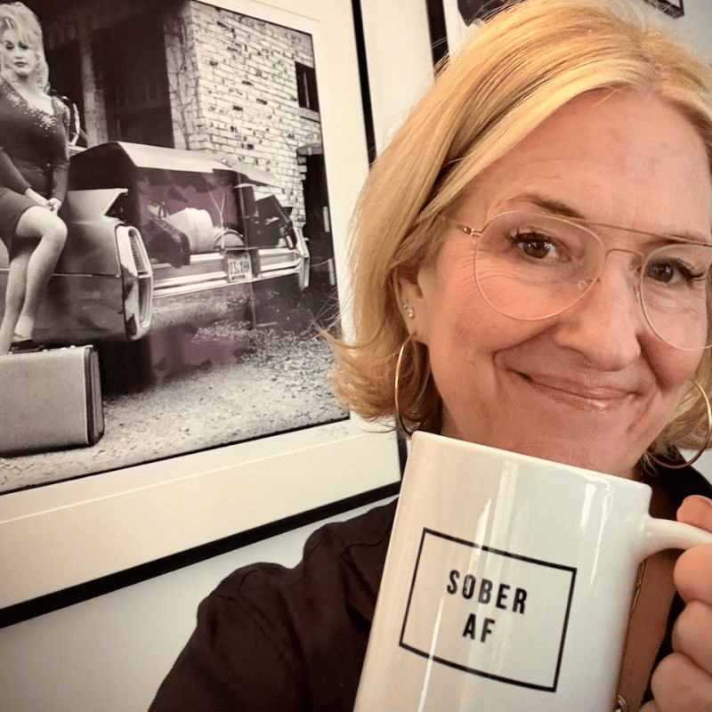 Woman smiles as she holds a sober AF coffee mug