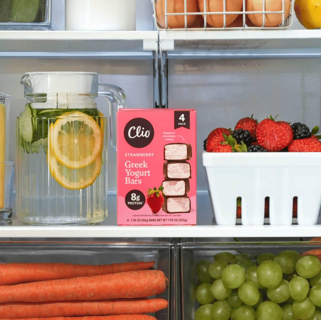 Box of 4 Clio yogurt bars in a fridge with strawberries, grapes, carrots, and water